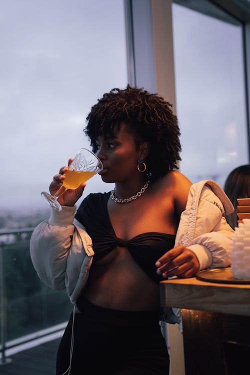 Woman in Black Brassiere and White Cardigan Holding Ice Cream Cone