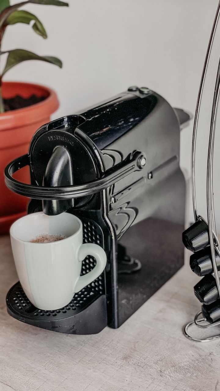 Black wire coffee pod holder mounted on the wall next to a coffee and tea bar