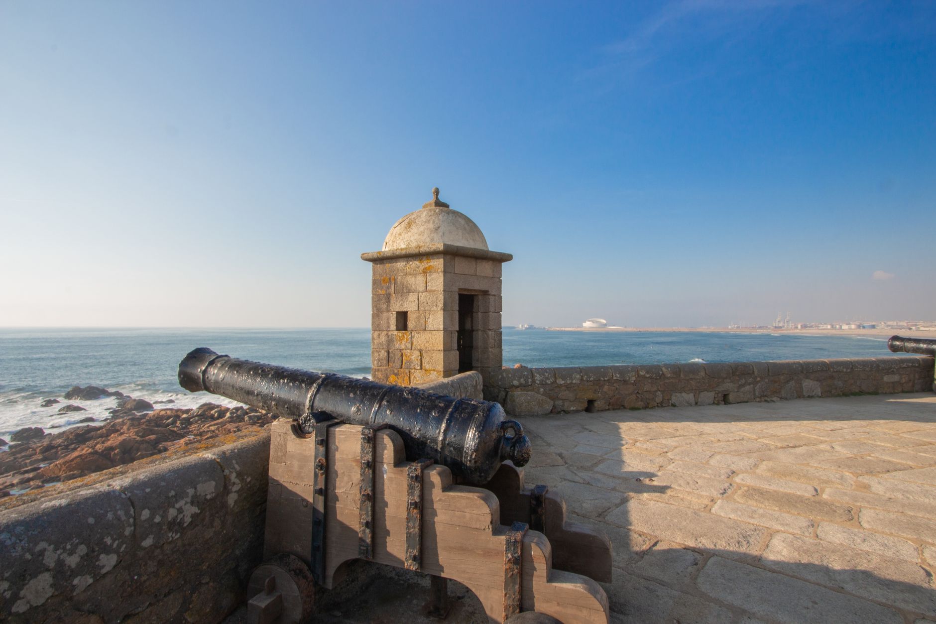 Antique cannon at a fortified structure in Porto, Portugal, with ocean views.