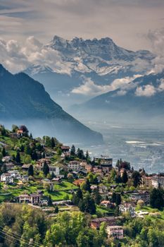 A picturesque Alpine village nestled among lush hills, framed by majestic mountains.