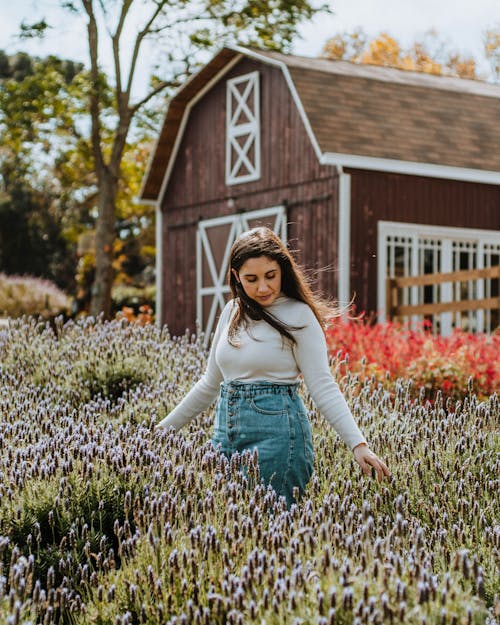 Woman in Gray Long Sleeve Shirt and Denim Pants Standing on Flower Field