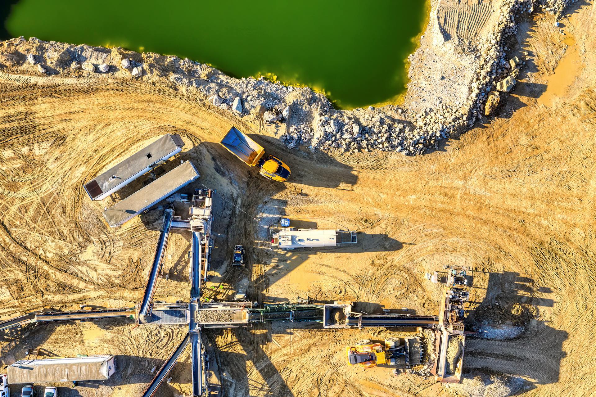 Top-down view of a construction site with trucks and equipment near a pond in Rochester, MN.