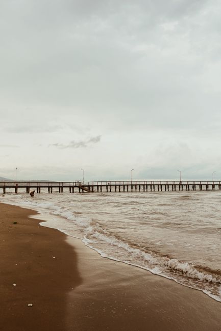 Peaceful view of waves crashing on a sandy shore with a long pier in Samsun, Turkey.
