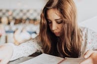 咖啡馆里，一位年轻女子正全神贯注地阅读菜单，营造出一种内省而舒适的氛围