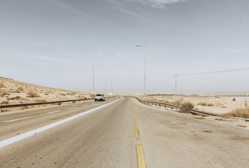 Free A deserted highway stretches through arid landscape under clear skies, exemplifying solitude. Stock Photo
