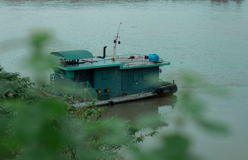 Free A serene houseboat floating on a tranquil river amidst lush greenery, perfect for travel and lifestyle themes. Stock Photo