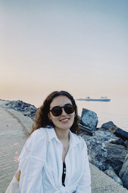 A Woman in White Long Sleeves Smiling while Wearing Sunglasses