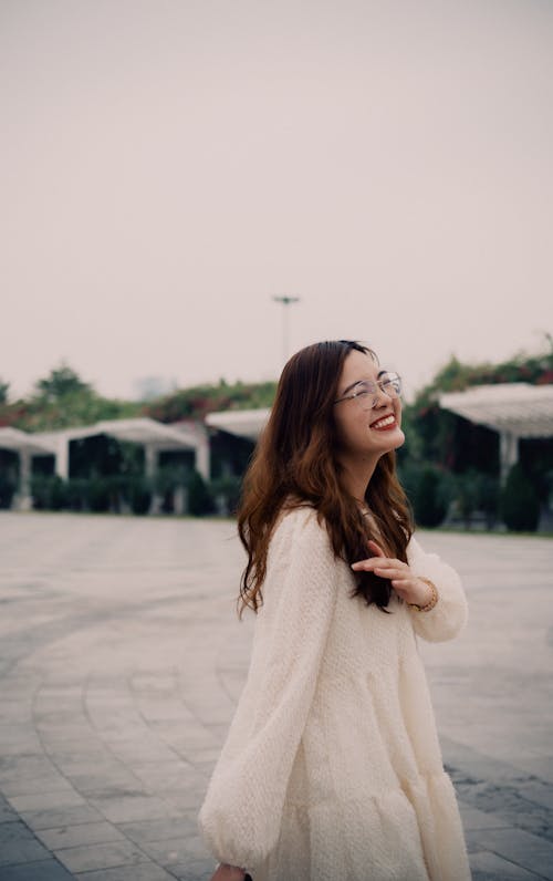 A Woman in White Dress Smiling while Wearing Eyeglasses