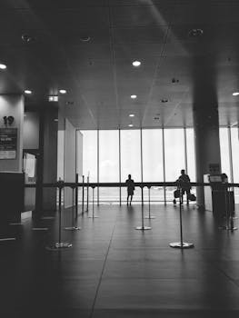 Black and white photo of a modern airport corridor with people and luggage in Bologna, Italy.