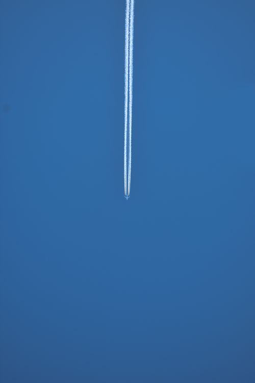 Free Captivating view of a jet airplane leaving a contrail against an expansive blue sky. Stock Photo