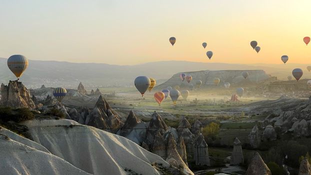 Majestic hot air balloons floating over Cappadocia's unique landscape during a beautiful sunrise.