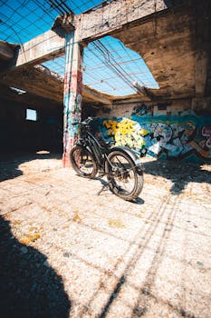 A bike sits in a sunlit, graffiti-covered abandoned building, highlighting urban decay.