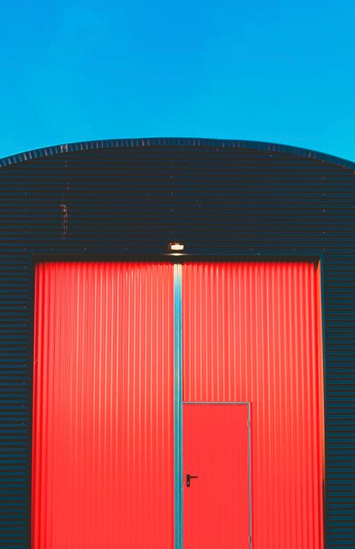 Free Close-up of a bright red corrugated metal hangar door with clear sky background. Stock Photo