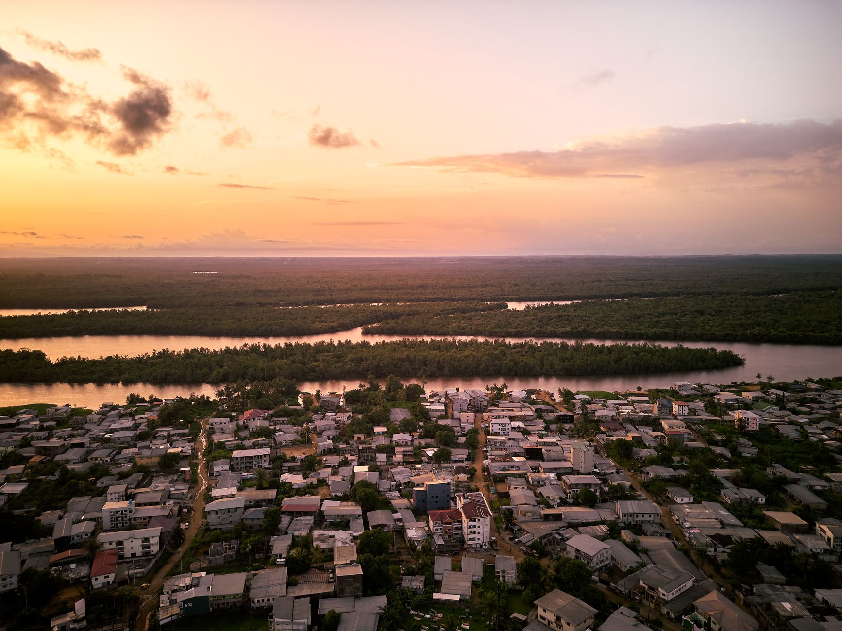 Stunning aerial view of Douala, Cameroon at sunset showcasing the river and urban landscape.