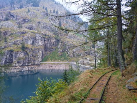 Breathtaking view of Antrona Schieranco dam and railway amidst rocky Italian landscape.