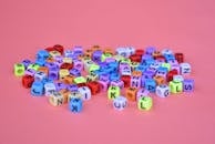 粉红色的背景上散落着充满活力的字母立方体珠子，非常适合创意项目