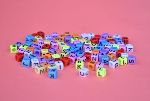 Free Vibrant alphabet cube beads scattered on a pink background, perfect for creative projects. Stock Photo