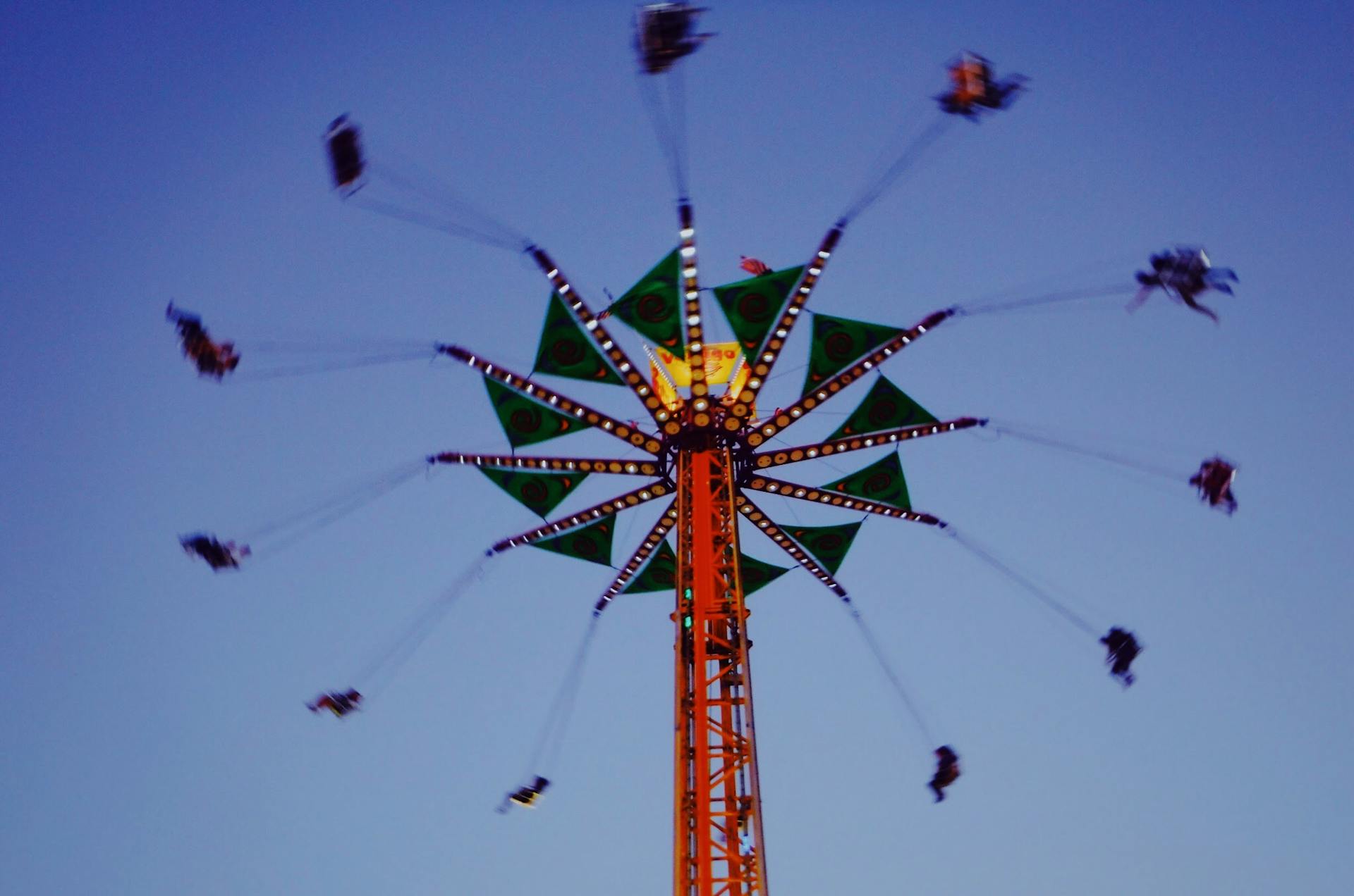Blurred motion of a carnival swing ride against a twilight sky, capturing an essence of fun and excitement.