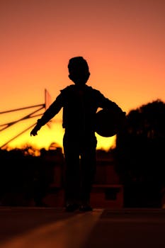 A child with a basketball silhouetted against a vibrant sunset, capturing the beauty of San Andrés Cholula, Mexico.