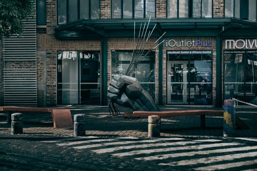 Striking urban sculpture by a crosswalk, showcasing city architecture and artistic elements.