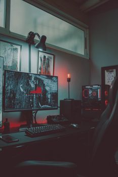 Stylish gaming setup featuring a monitor, keyboard, and illuminated PC in a cozy room with red LED lighting.
