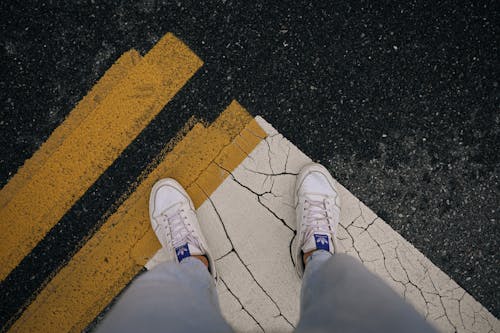 Person Standing in White Nike Sneakers on Asphalt Ground