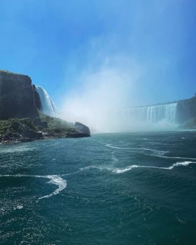 Majestic Niagara Falls with cascading water under clear blue sky, showcasing nature's grandeur.