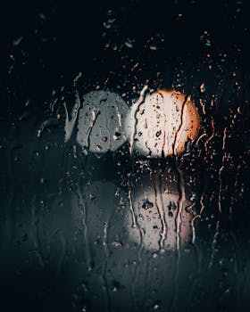 Artistic capture of raindrops on a window with blurred city lights creating a moody ambiance.
