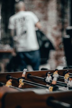 Close-up of a foosball table with blurred background in an indoor setting.