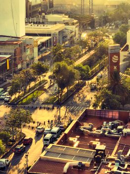 Captivating aerial view of a city street with trees and buildings during sunset, showcasing urban life.
