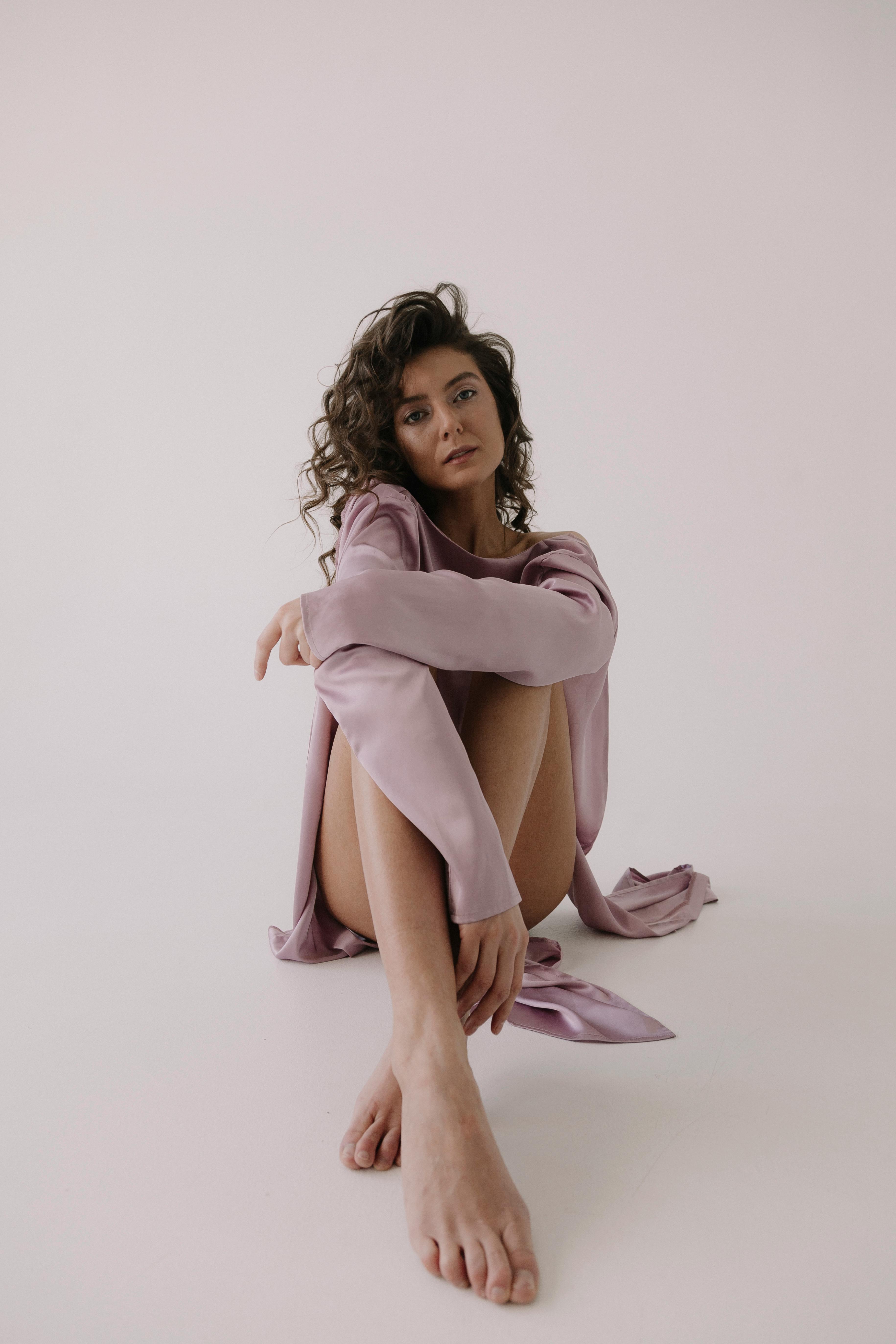 一位美丽的黑发女子坐在白色背景上，在柔和的自然光线下