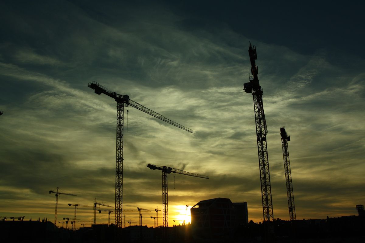 Construction cranes at a building site during sunset