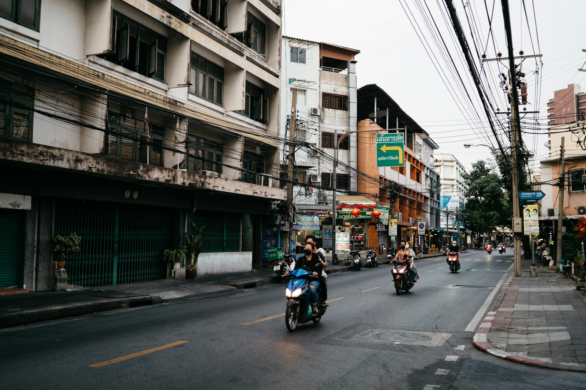 People Riding on Motor Scooters on a Street in a Thai City