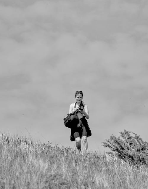 Grayscale Photo of a Photographer Walking in a Field