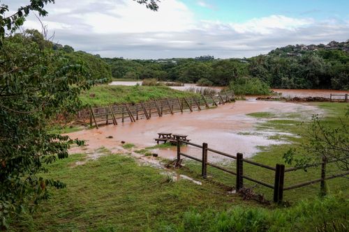 Free A scenic view of a rural field flooded with water, featuring a broken fence and lush greenery. Stock Photo