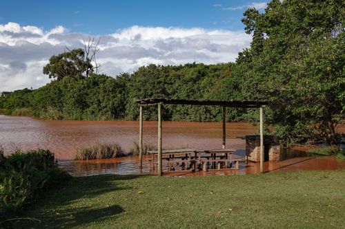 Free A flooded picnic area with a gazebo by a lakeside, surrounded by lush greenery. Stock Photo