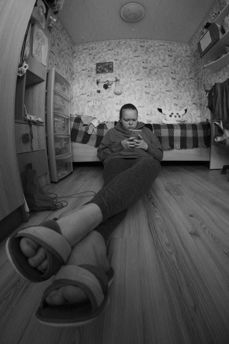 Wide Angle Shot Of A Girl Sitting On The Floor With Her Phone 