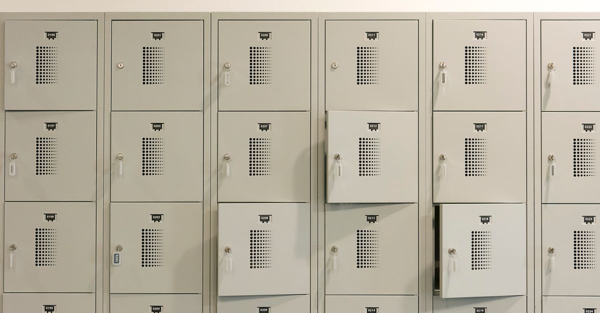 Una fila de taquillas metálicas grises en interiores con algunas puertas entreabiertas.