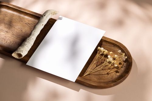 Free Close-up of a wooden tray with blank paper and dried flowers, perfect for mockups. Stock Photo