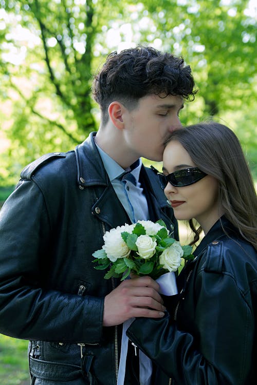 Free Man Kissing a Woman Holding White Rose Bouquet Stock Photo