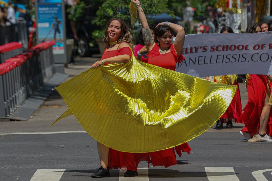 Performers in vibrant costumes dance in a lively street parade in New York City, capturing the spirit of cultural celebration.