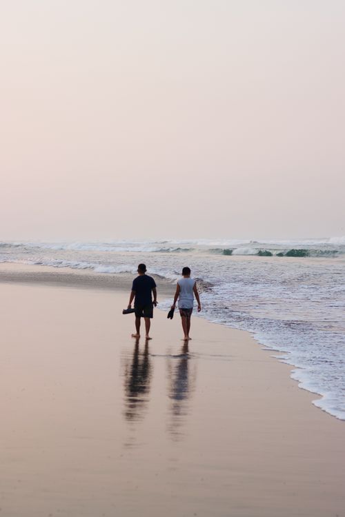 Free A serene scene of two people walking along Acapulco beach at sunset, capturing a peaceful moment. Stock Photo