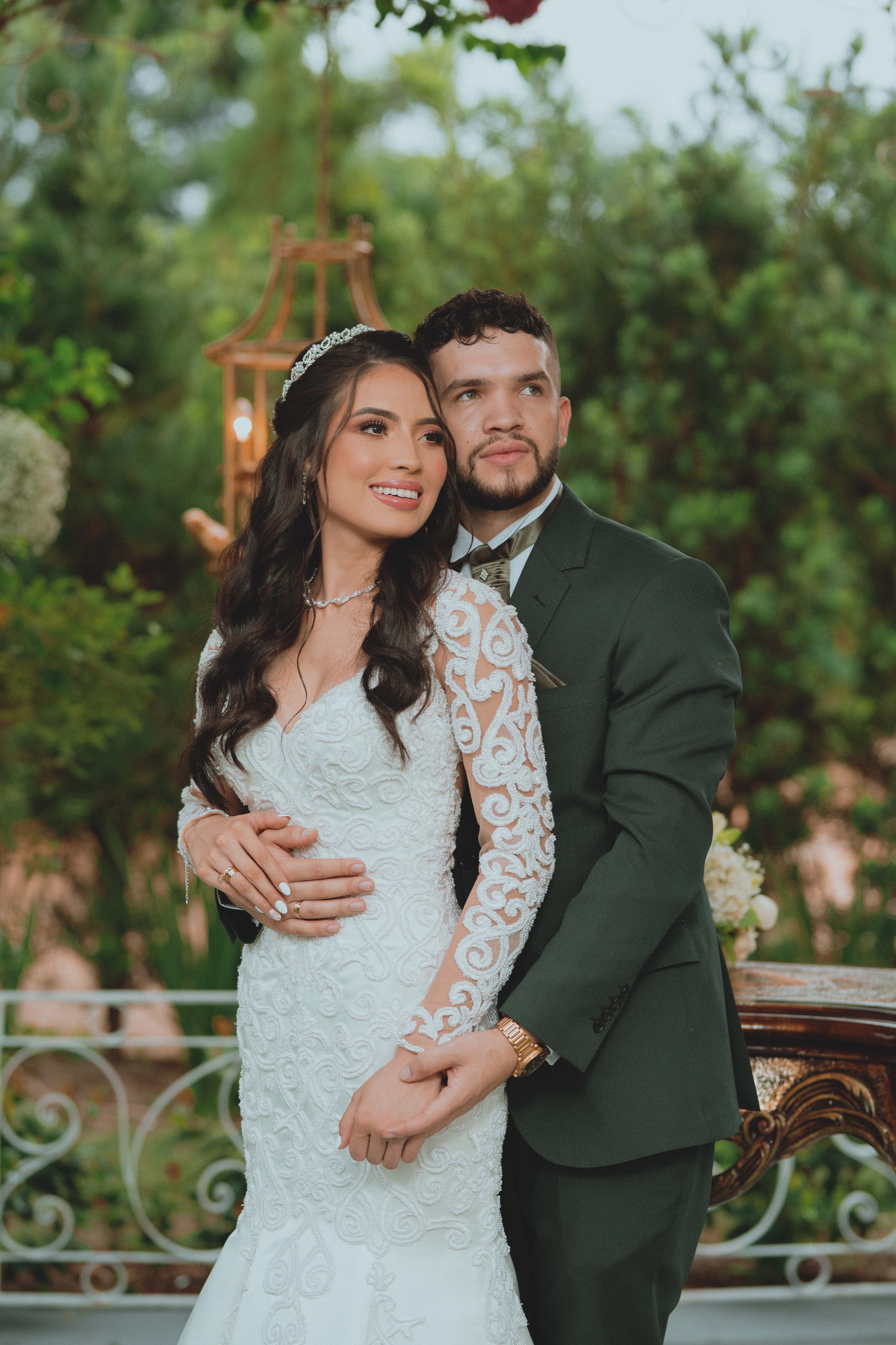 Romantic photo of a newlywed couple embracing outdoors in a lush garden, exuding joy.