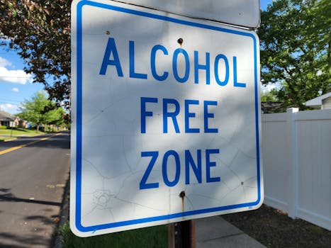 A street sign indicating an alcohol-free zone in a suburban area with clear blue skies.