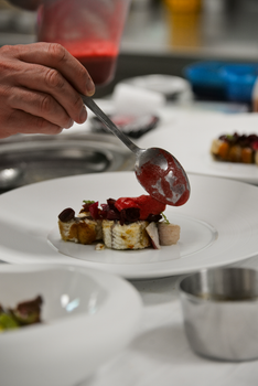 Chef skillfully plating a gourmet dish in a professional kitchen setting.