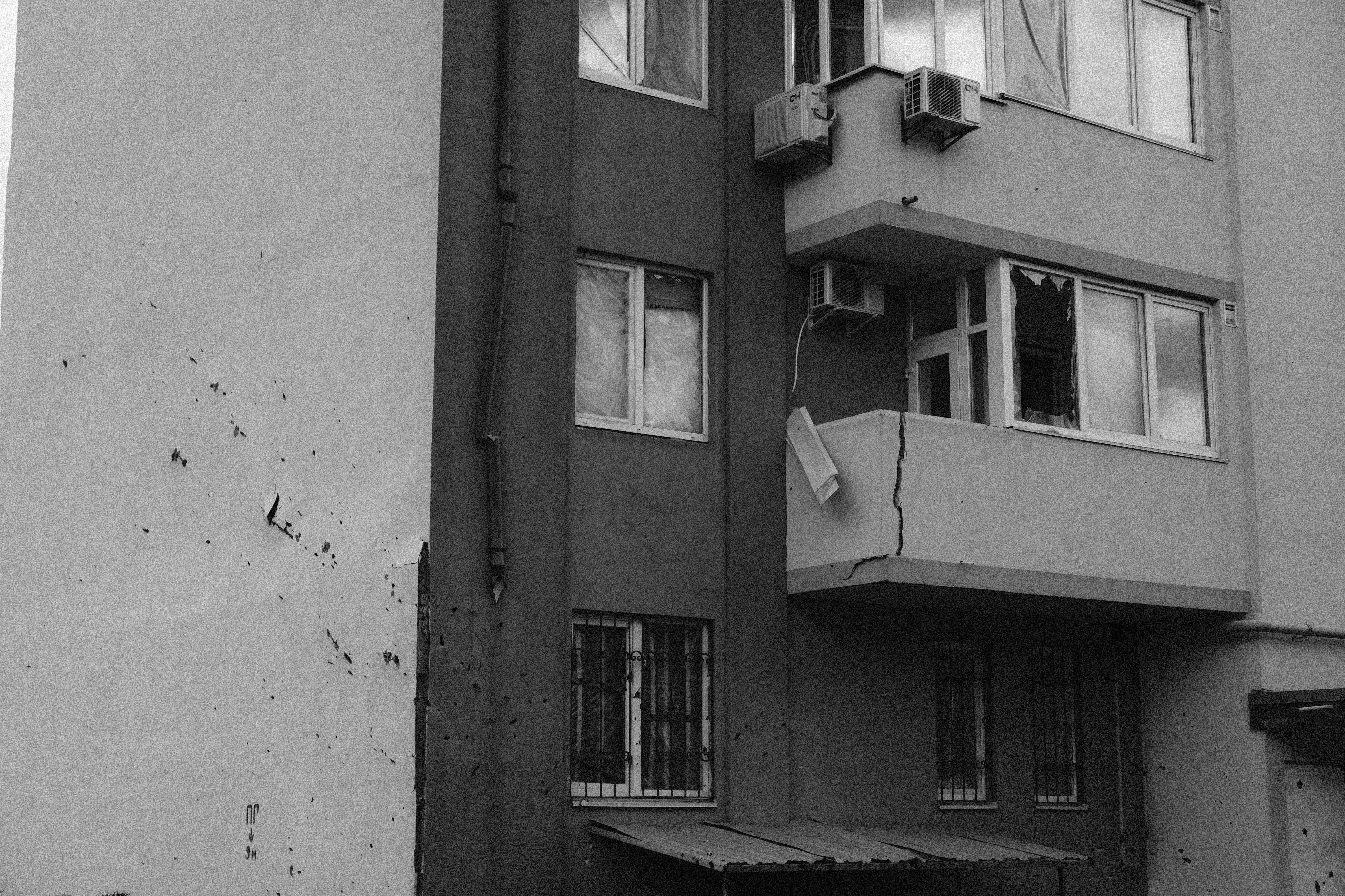 Grayscale image of a damaged building facade in Kyiv, showcasing structural impacts.