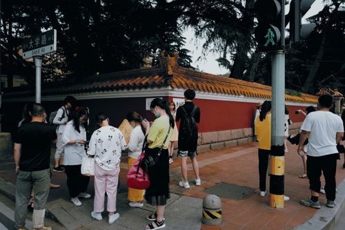 Free A diverse group of people standing at an urban crosswalk, using smartphones, highlighting daily life. Stock Photo