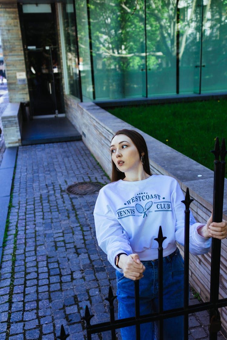 Photograph Of A Girl Holding A Fence While Looking Away