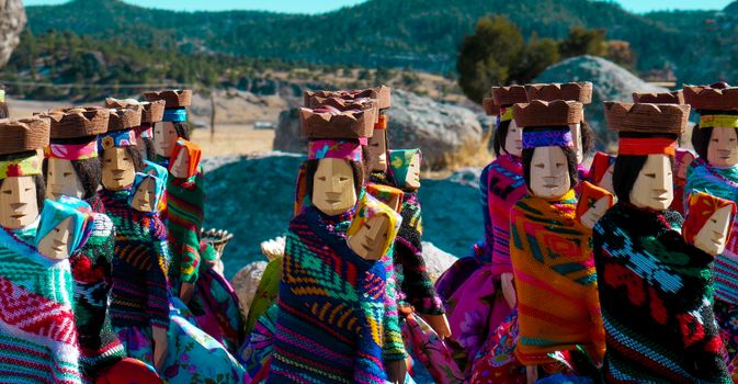 Vibrant wooden figures in traditional costumes representing Mexican culture outdoors.