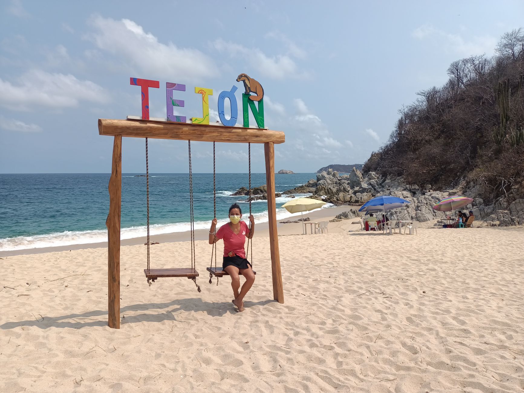Woman enjoys a swing with safety mask on Tejon Beach, Oaxaca.